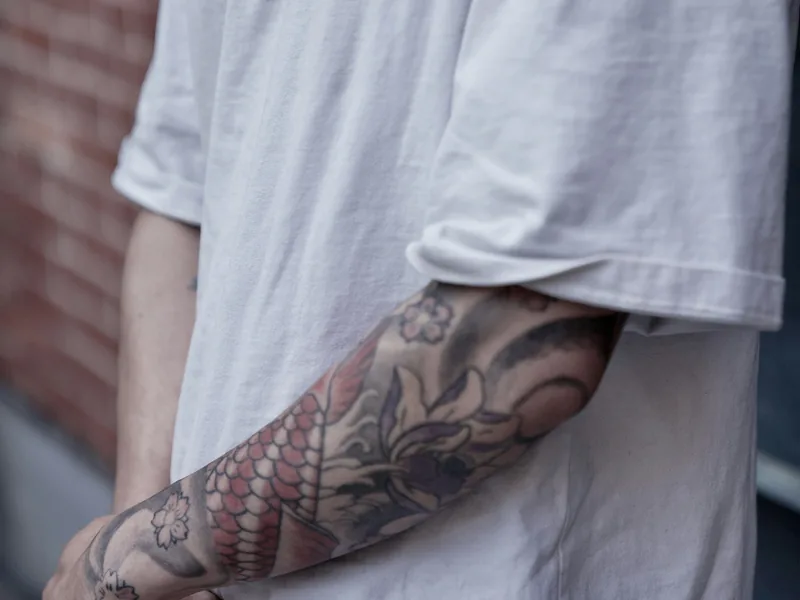 Man in a white T-shirt with a black and grey sleeve, the kind of visible tattoo that raises government job questions in Malaysia