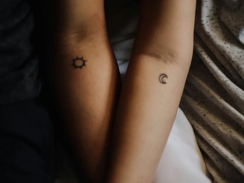 Couple holding hands with matching sun and moon tattoos