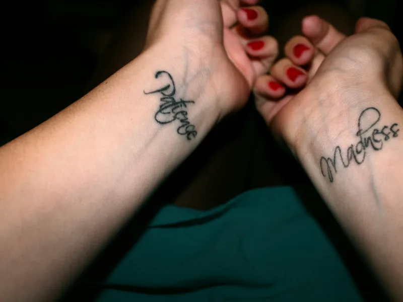 Two small script tattoos on a pair of wrists
