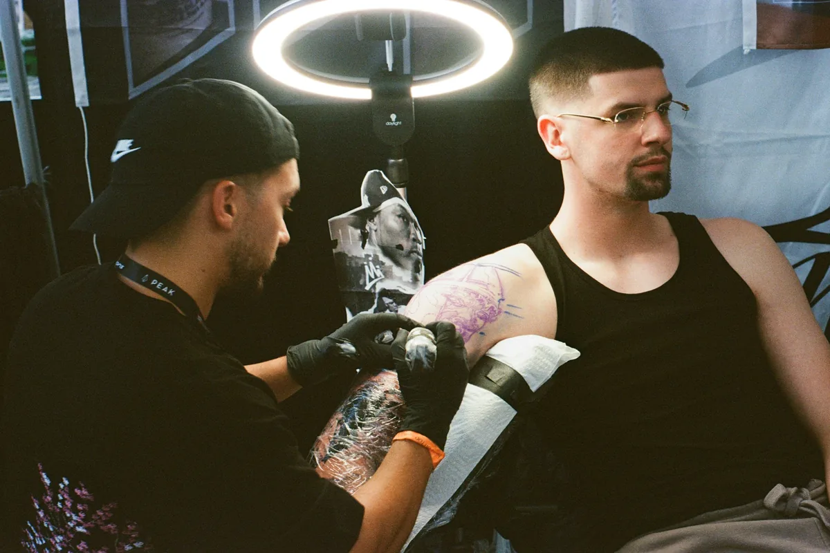 Tattoo artist working on a client's colour sleeve under a ring light, the kind of detailed work that may need a tattoo touch up after healing