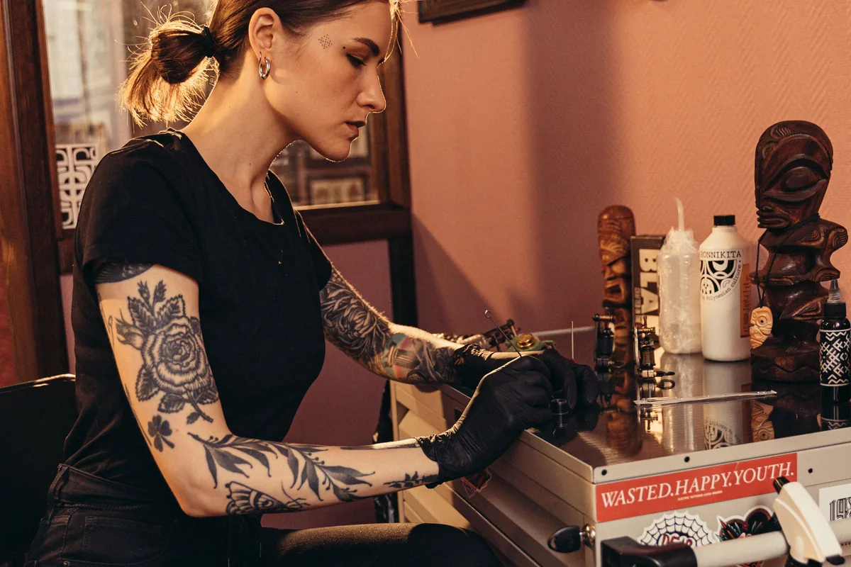 Tattooist in gloves setting up her station before a session, a key thing to watch when you choose a tattoo artist